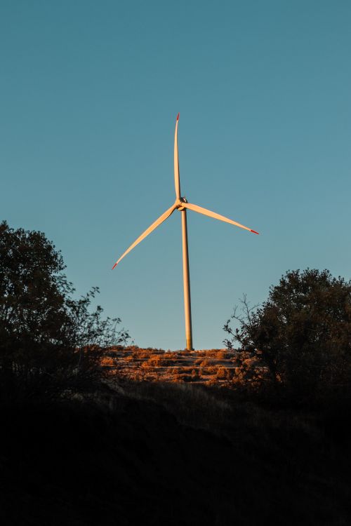 Free A wind turbine in a rural setting during sunset, capturing renewable energy in nature. Stock Photo