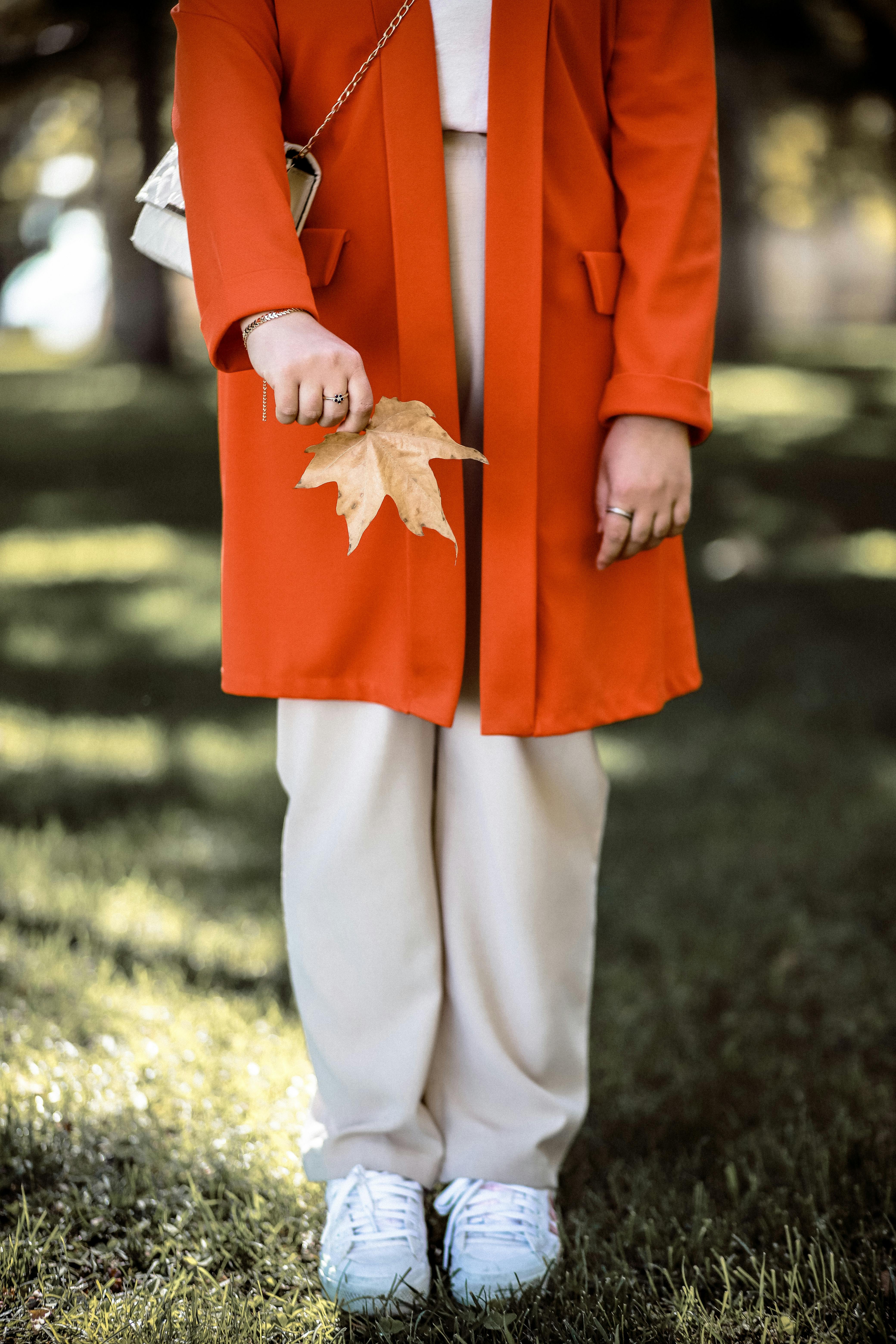 Stylish autumn fashion in Niğde, Turkey, featuring orange coat and leaf.