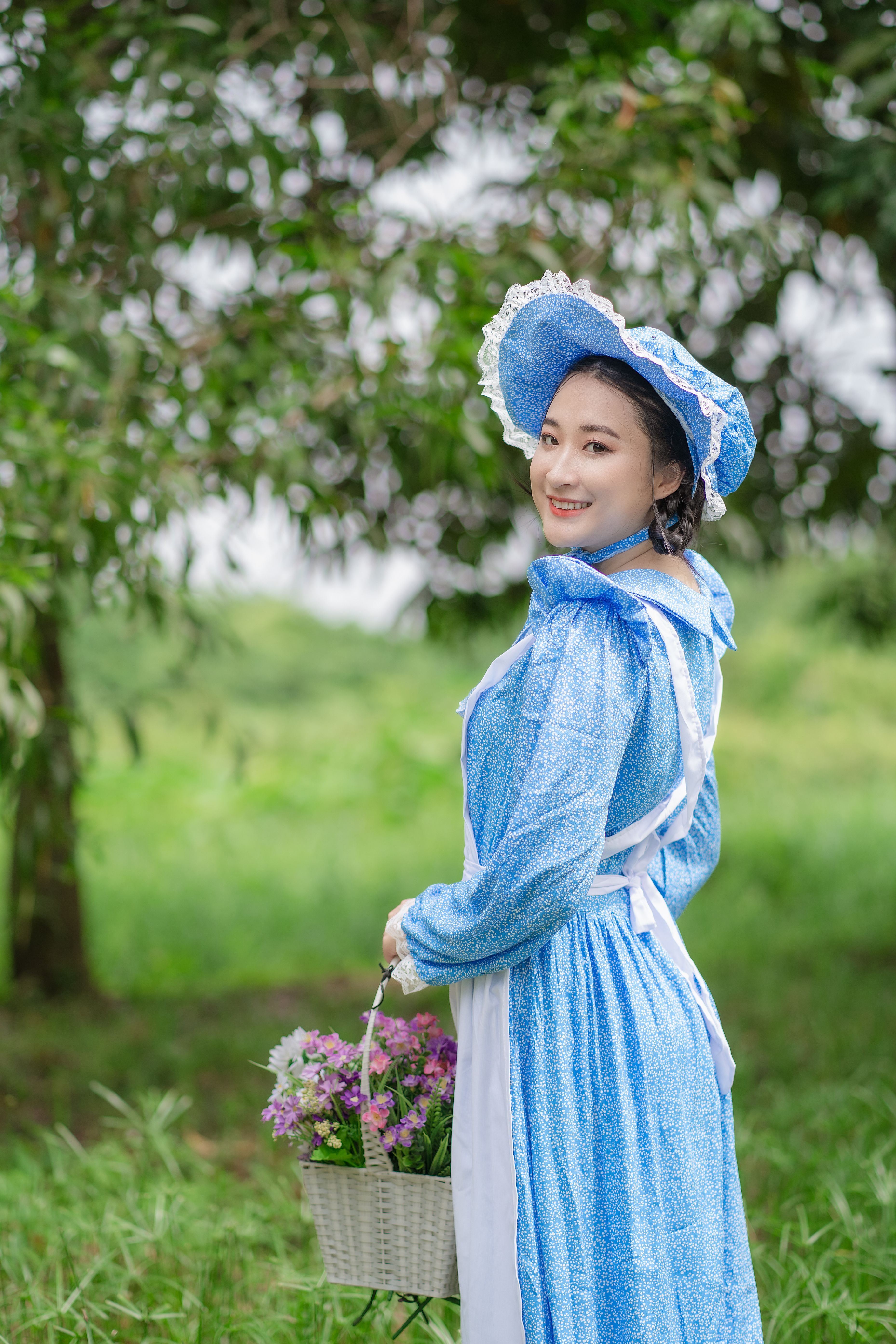 Charming woman in a blue vintage dress holding flowers, exuding summer joy in a lush garden.