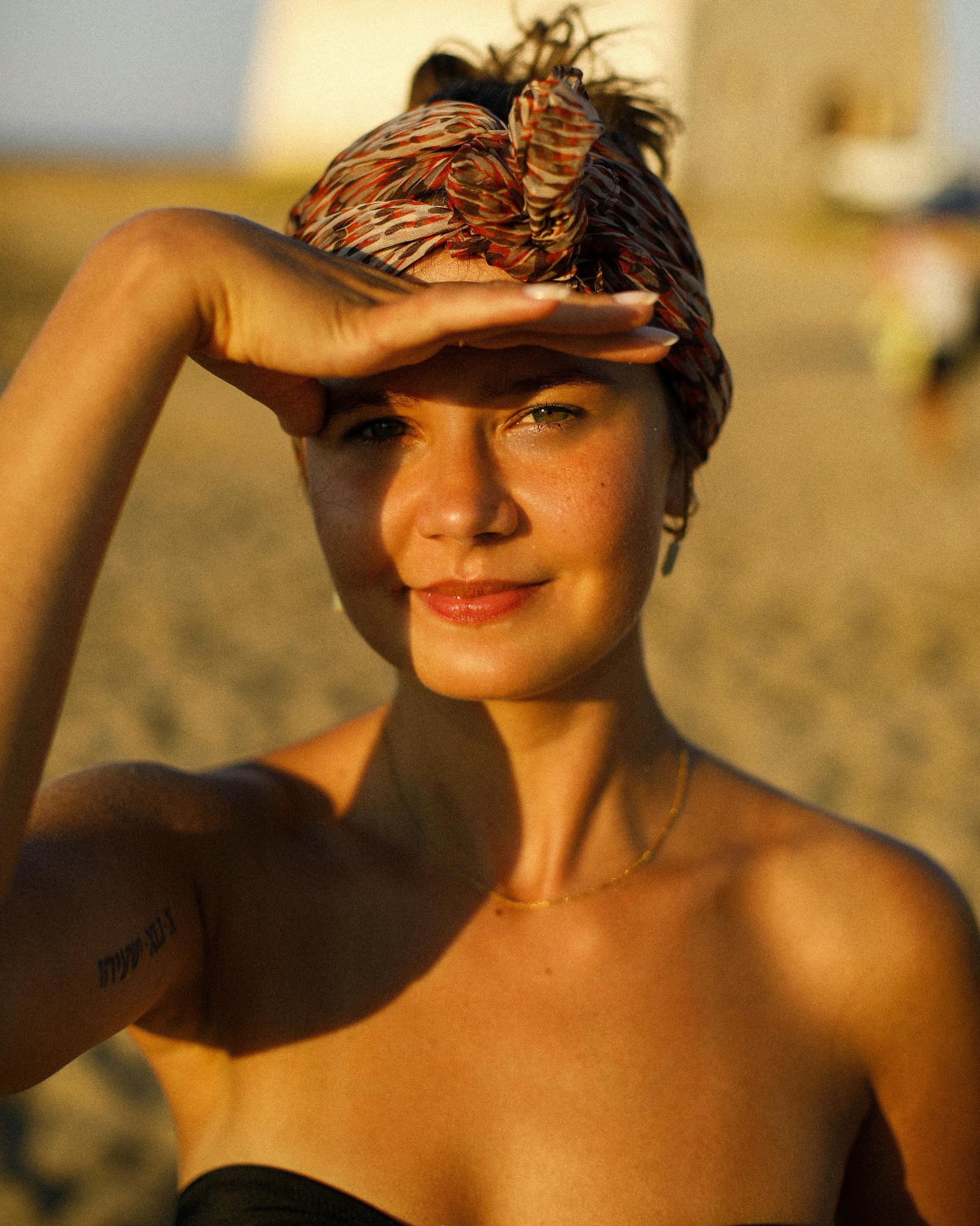 A woman enjoying a sunlit day on the beach in Apulien, Italy, shielding her eyes.