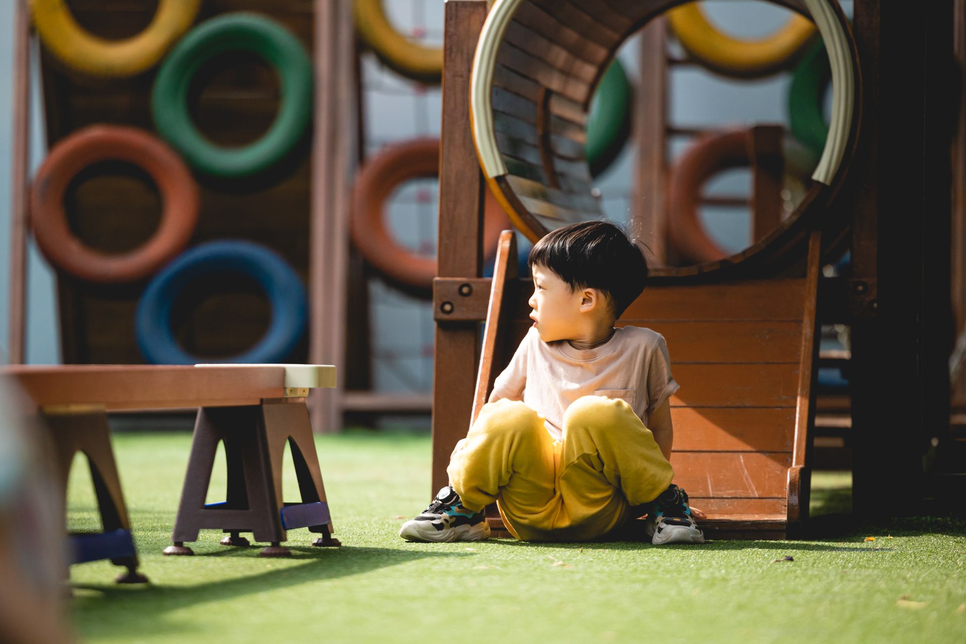 A young boy plays on colorful playground equipment during a sunny day.