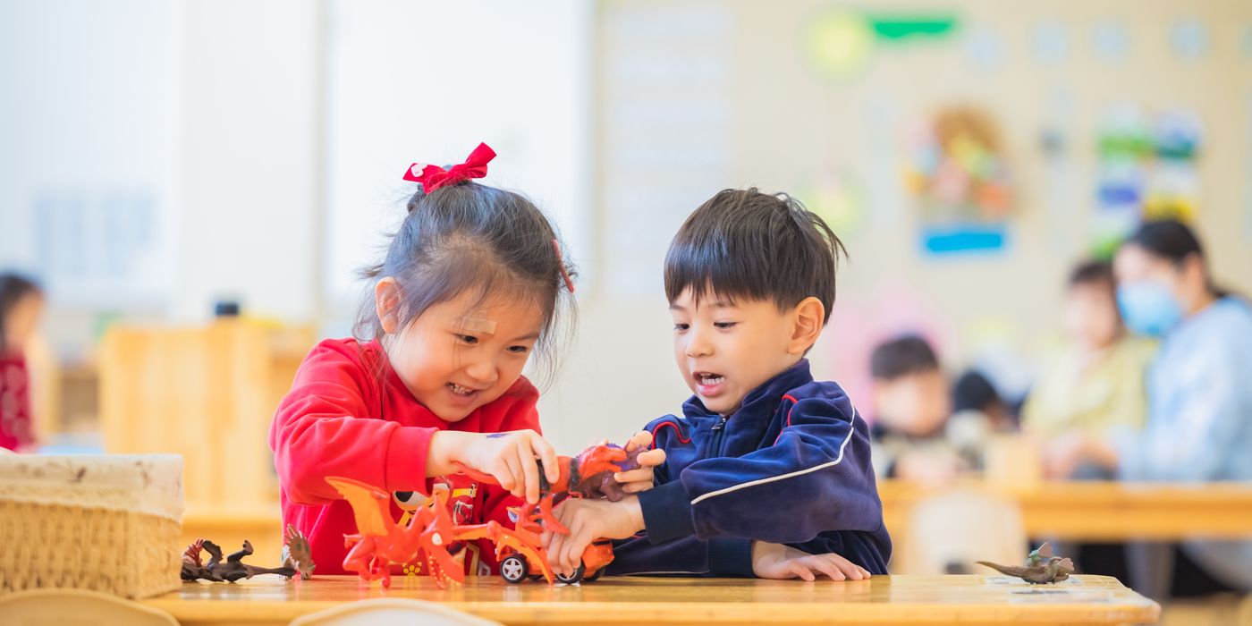 Two kids enjoy playing with toys in a lively kindergarten setting.