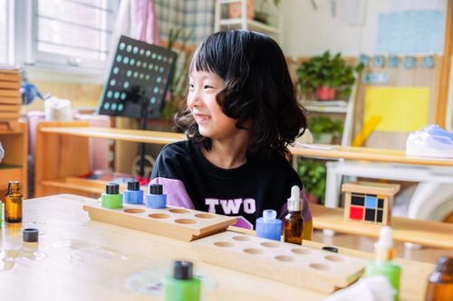 Free A cheerful young girl enjoying educational activities in a bright classroom environment. Stock Photo
