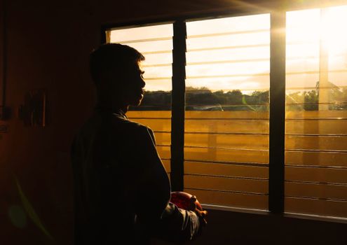 A silhouette of a man standing by a window at sunset in Batangas, Philippines.