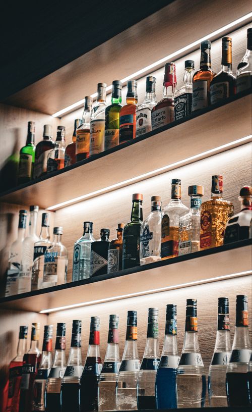 Free A vibrant display of assorted liquor bottles on illuminated bar shelves. Stock Photo