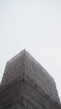 Low angle shot of a building covered in scaffolding under a clear sky.