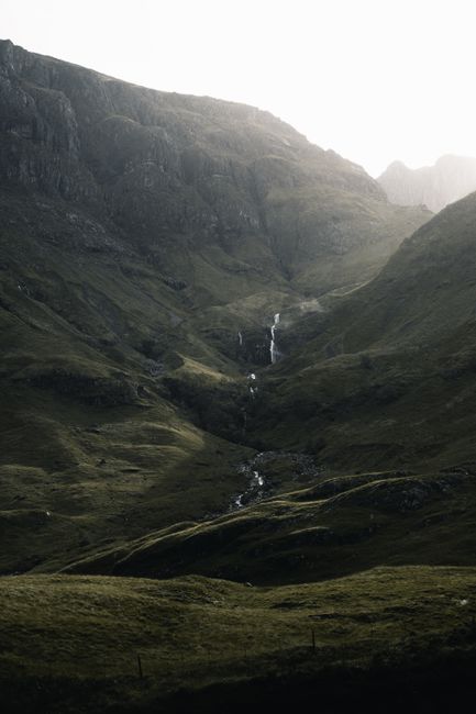 Captivating view of Glencoe's rolling hills and waterfall in Scotland's Highlands.