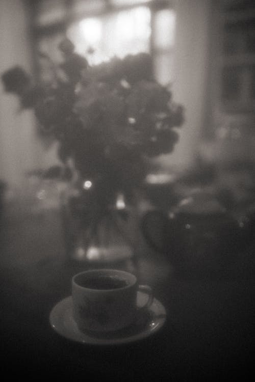 Free Black and White Shot of a Cup of Coffee and a Bouquet of Flowers  Stock Photo
