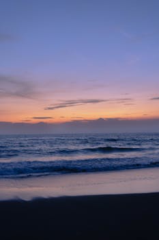 A tranquil sunset view over Tainan's beach with gentle waves and vibrant sky.