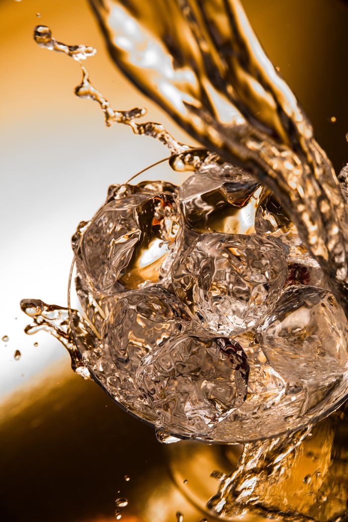 Ice cubes splashing in water with a warm golden hue