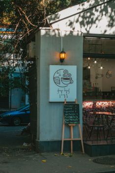 Cozy outdoor view of a quaint urban café with a menu board and warm lighting.