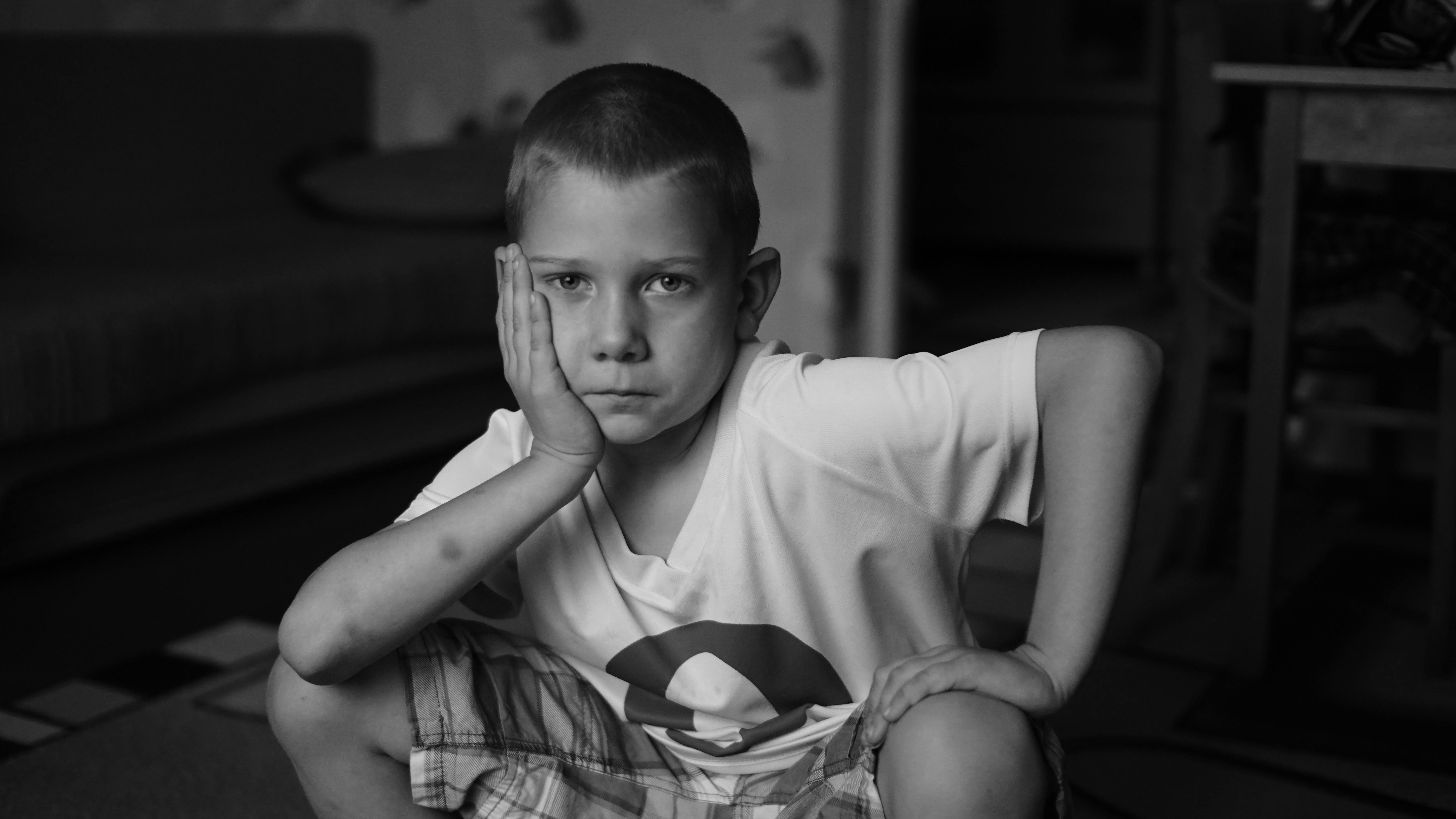 a black and white photo of a boy sitting on the floor