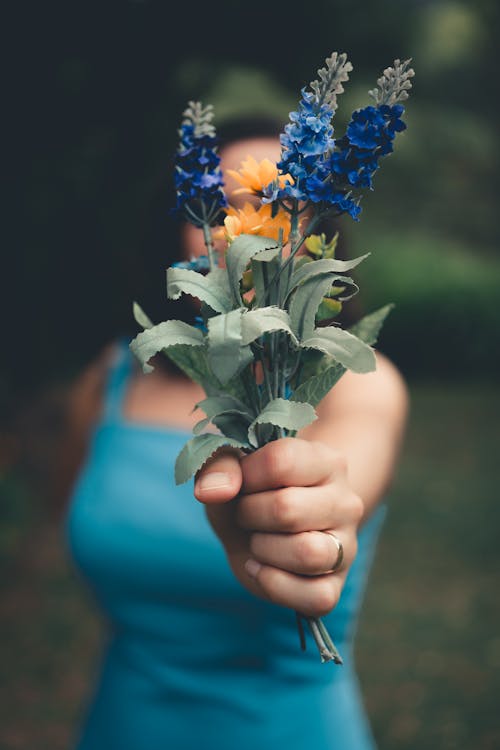 婦女拿著藍色瓣花的選擇聚焦攝影
