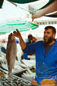 Experienced fisherman holding a fresh catch at a bustling fish market in Ankara, Türkiye.