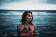 一位年轻女子站在海滩上，以海浪为背景，享受着一整天的时光