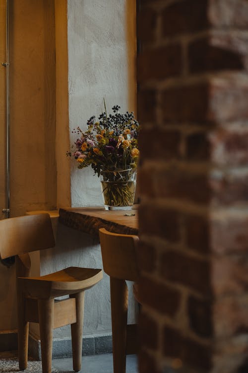 Wooden Three Legged Chairs at a Table with a Vase of Flowers