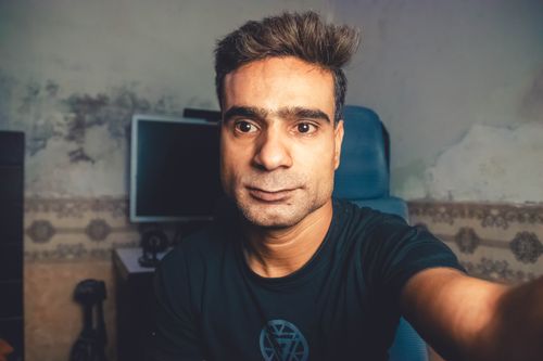 Free Man taking a casual selfie indoors, sitting in a home environment. Stock Photo