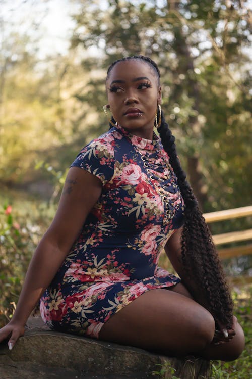 Woman Wearing Blue-and-pink Floral Crew-neck Bodycon Mini Dress Sitting on Rock