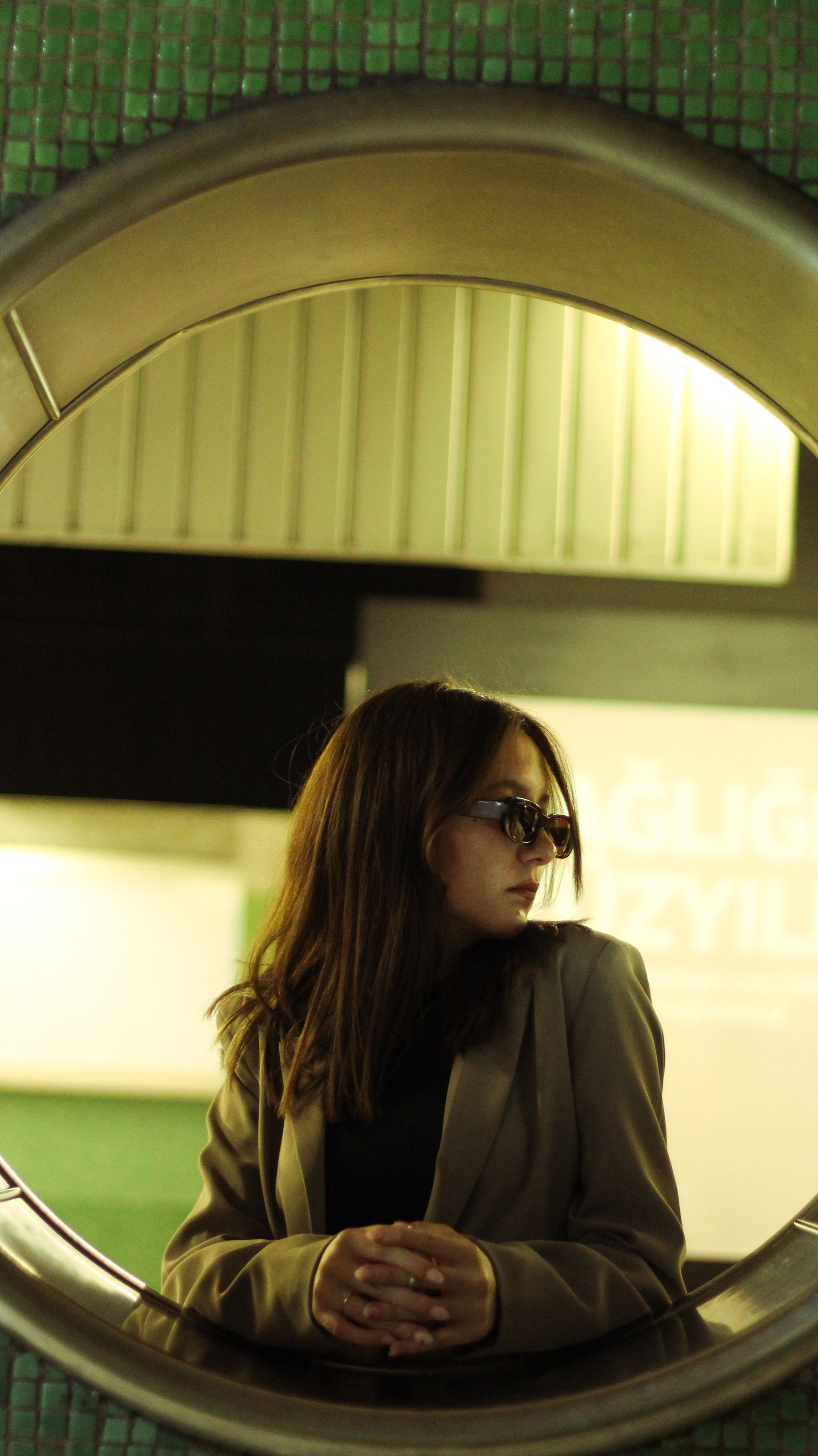 Stylish woman in sunglasses and jacket, elegant urban backdrop, contemporary look.