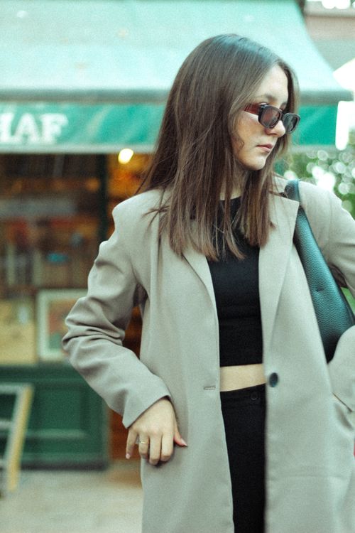 Free Stylish woman in a coat and sunglasses posing confidently in an urban setting. Stock Photo
