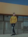 一名穿着时尚黄色毛衣的男子在现代户外背景下摆姿势