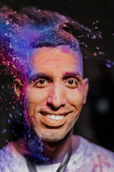 在节日庆祝活动中，一名男子高兴地拥抱鲜艳的色彩，身上裹着鲜艳的粉末