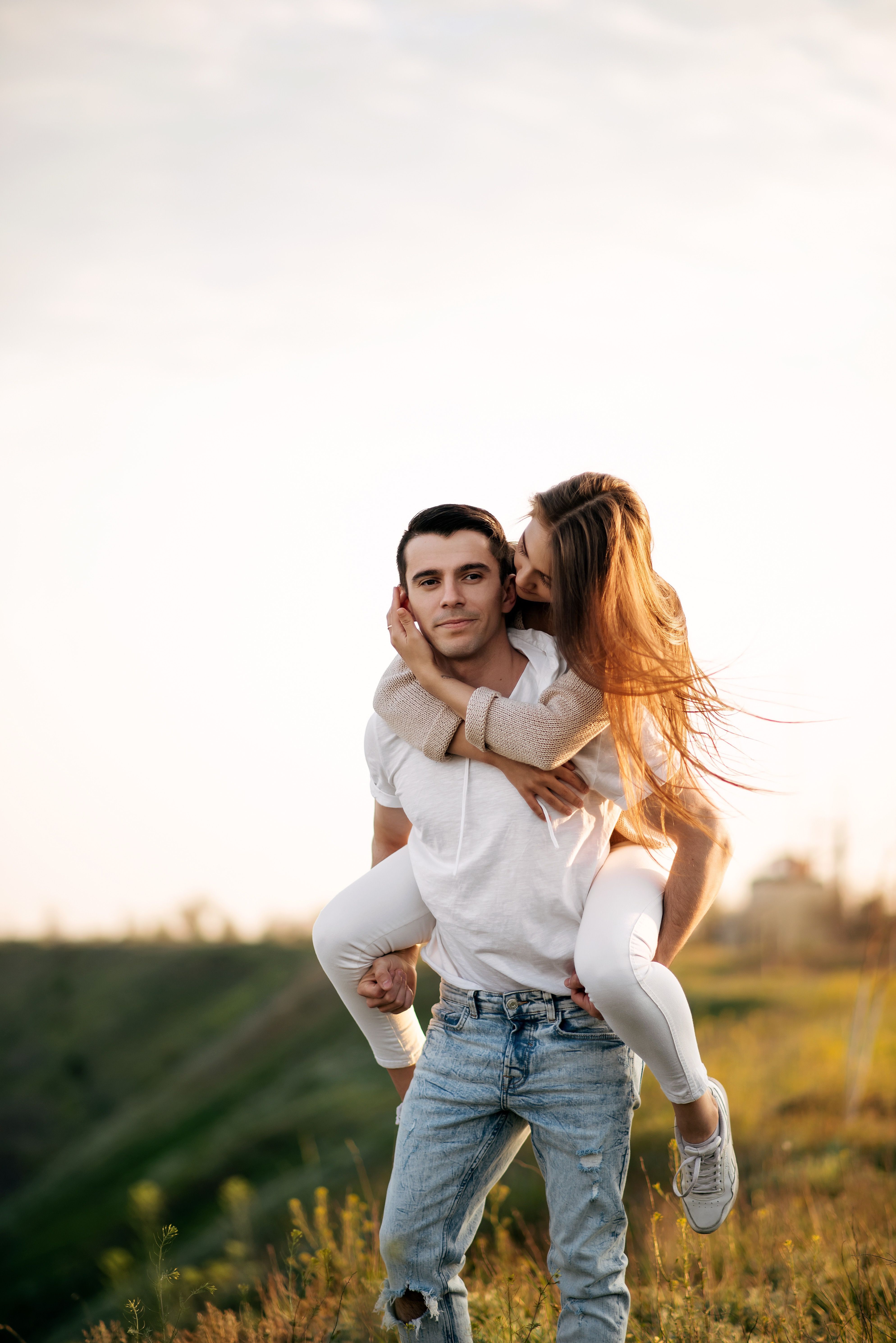 Young couple embracing outdoor fun during sunset, capturing love and togetherness.