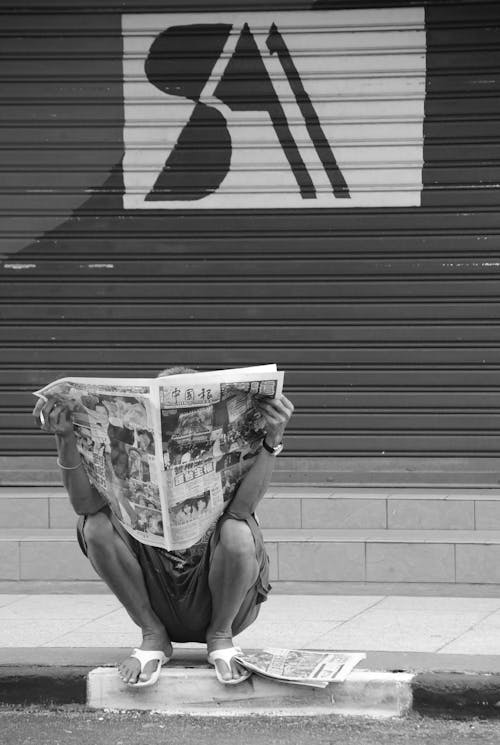 Orang Yang Duduk Di Sisi Jalan Membaca Koran