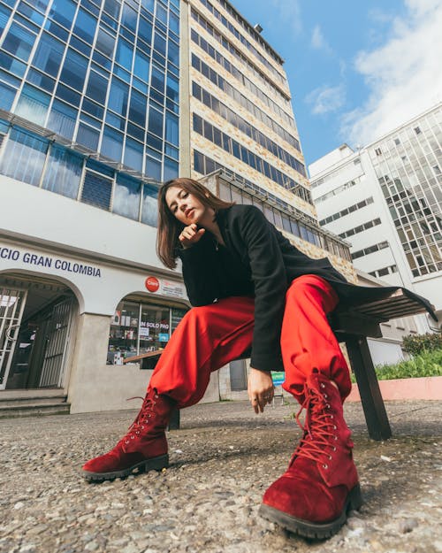 Model in Red Pants and Suede Boots Sitting on a Bench