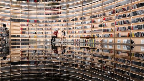 Free Expansive library interior with reflective floor and modern bookshelf design. Stock Photo