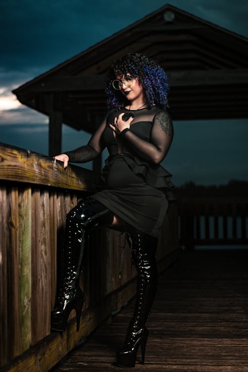 Portrait of a Female Model Wearing a Black Dress and Thigh High Boots Posing Outdoors at Dusk