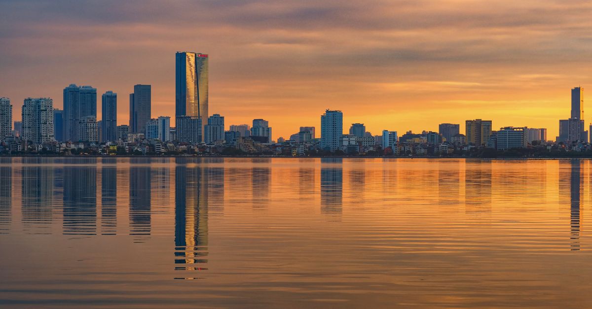 Captivating Hanoi skyline reflecting on the water during a stunning sunset in Vietnam.