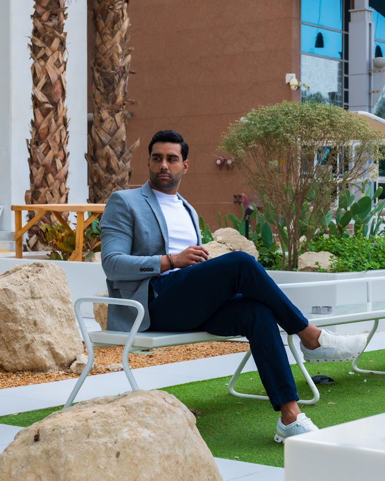 Man In Light Blue Blazer And Dark Blue Chino Pants Sitting On A Bench