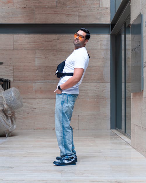 Fashionable Man Wearing Jeans and White T-shirt Standing in a Modern Building 