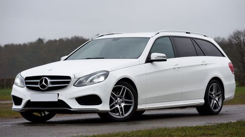 Free A sleek white Mercedes E-Class wagon parked outdoors under a cloudy sky, showcasing elegance and performance. Stock Photo