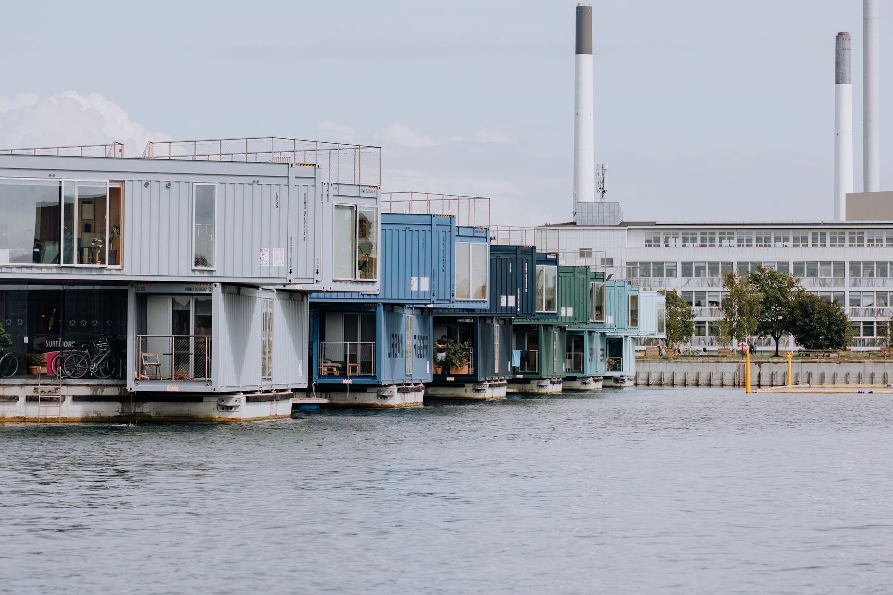 Modern container homes with dark cladding beside water