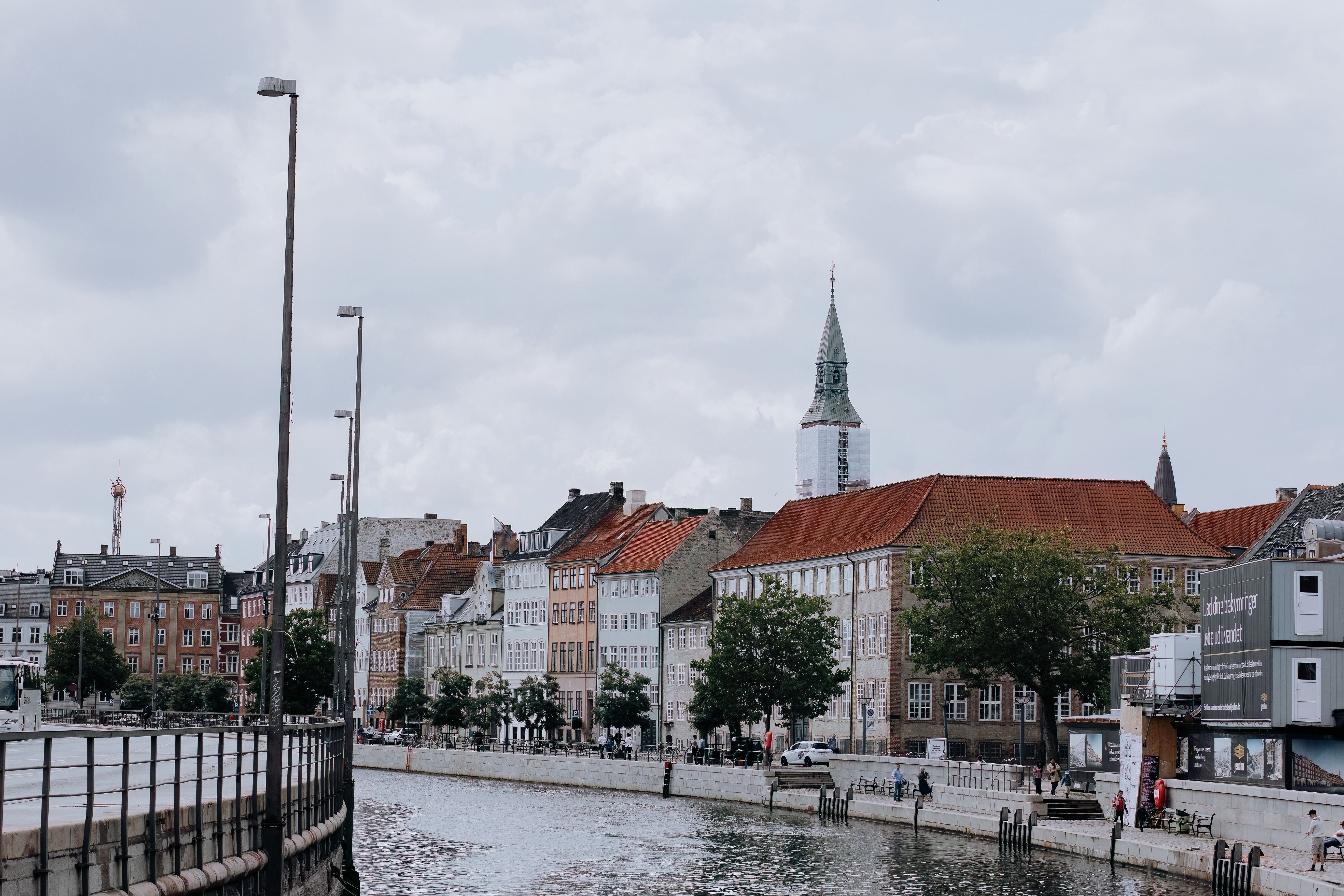 Scenic view of historic buildings along Copenhagen's waterfront under a cloudy sky.