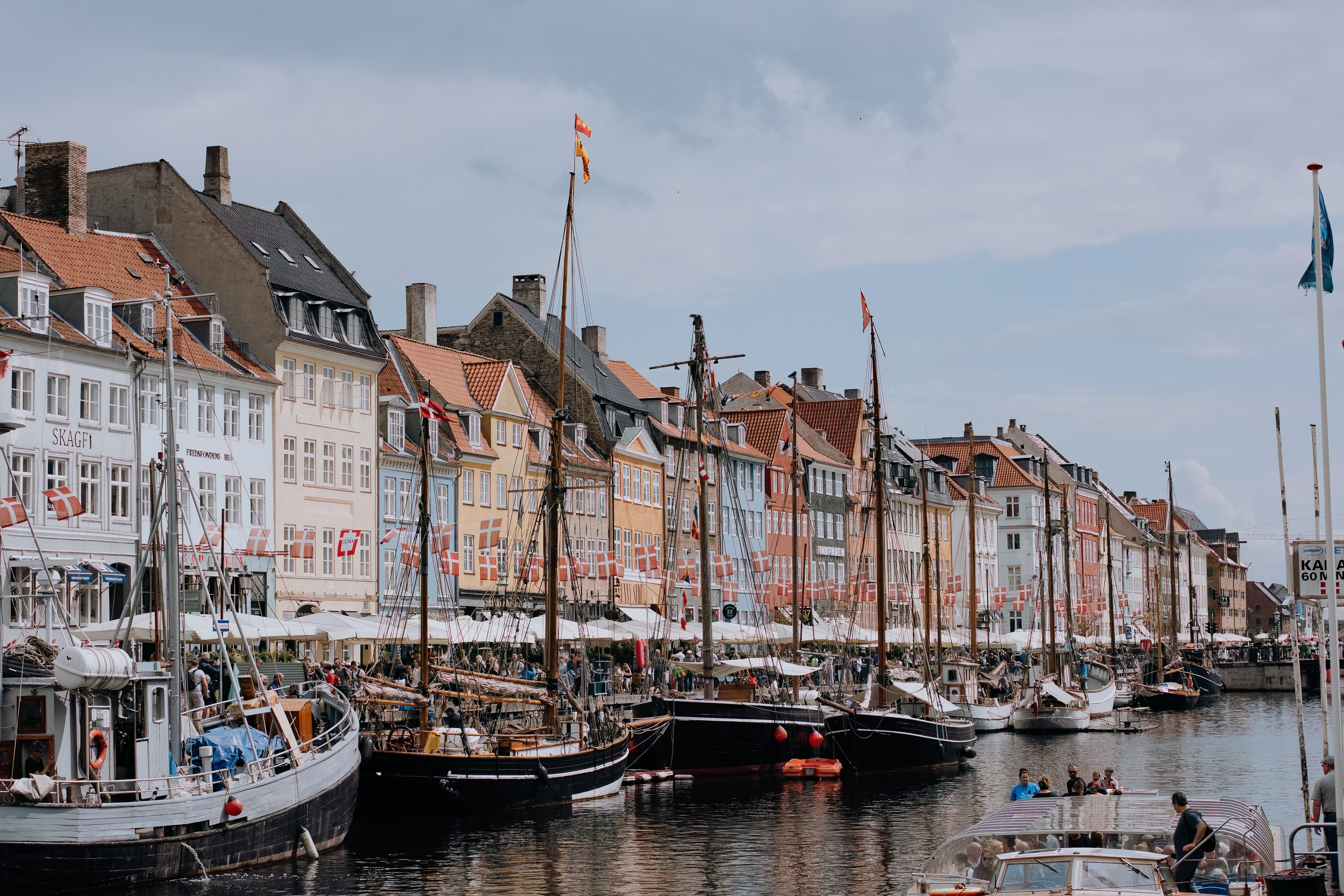 Charming waterfront scene of Nyhavn, a popular tourist area in Copenhagen with colorful buildings and moored boats.