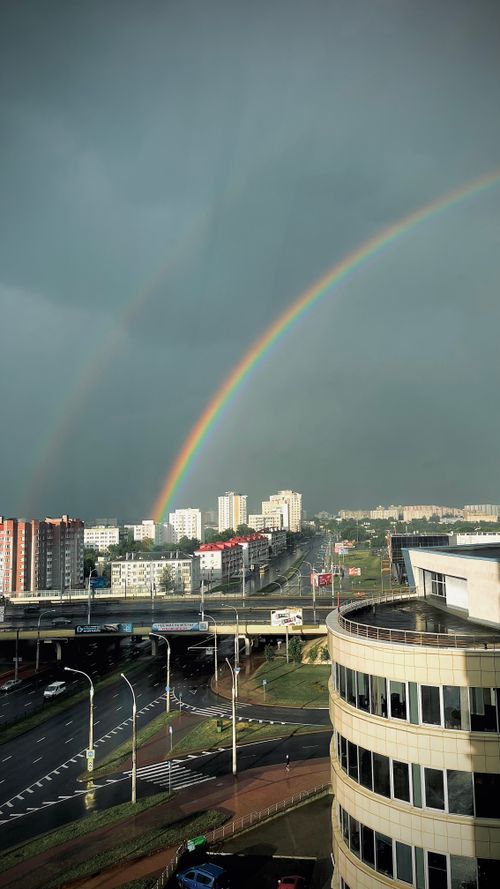 Free Vibrant rainbow over a rainy urban cityscape, capturing the blend of nature and architecture. Stock Photo