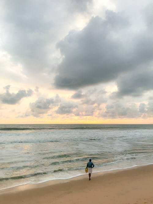 A Person Walking Alone on the Beach at Sunset 