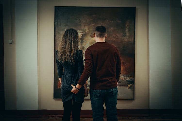 Couple Looking At Painting In Art Gallery