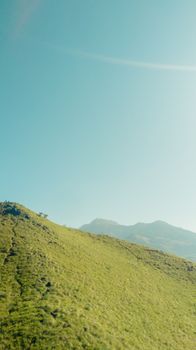 A tranquil landscape of rolling green hills against a bright, clear sky. Ideal for nature themes.