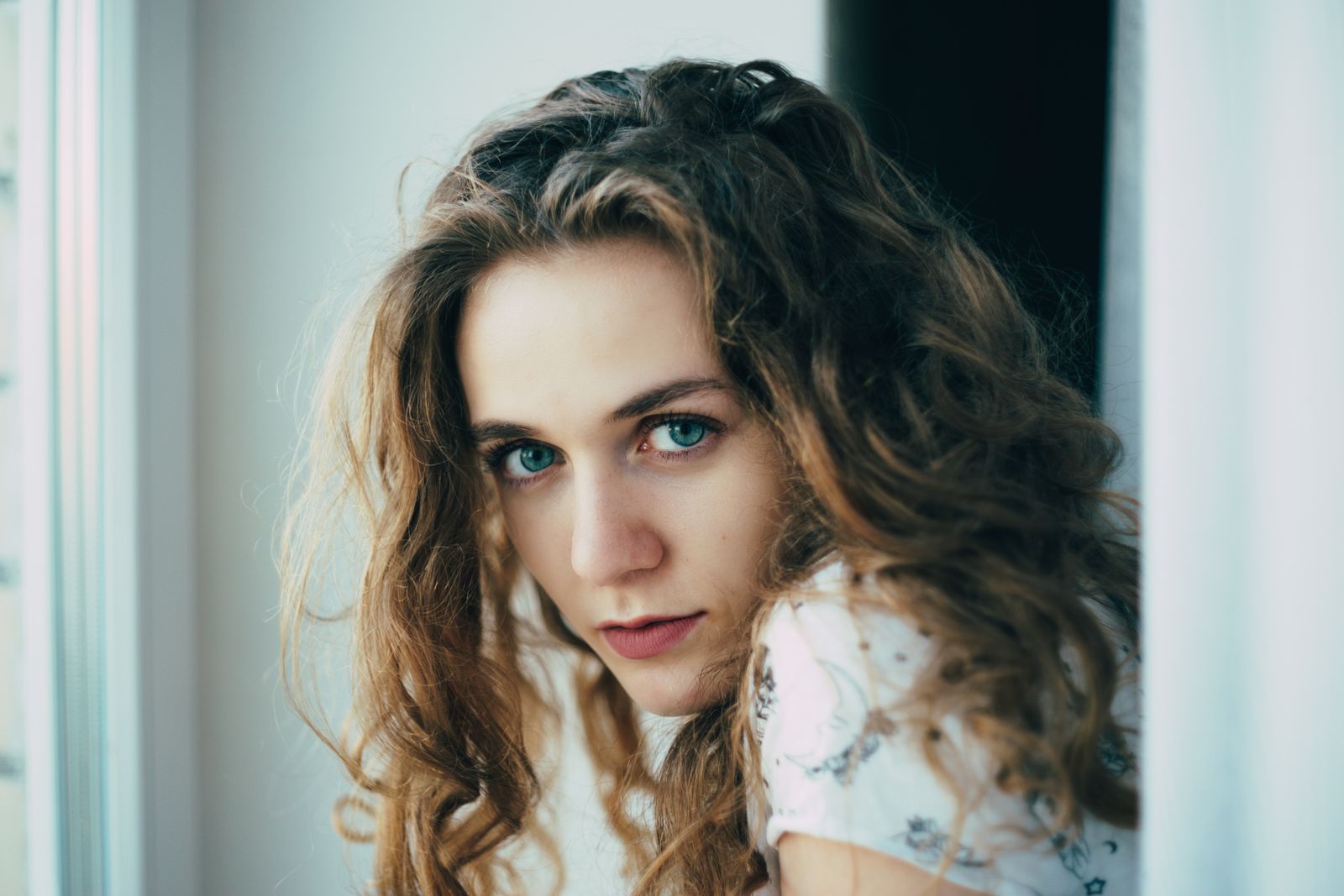 Woman with long wavy brown hair by a window