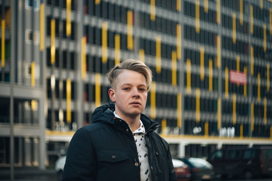 A young man in a dark coat on a city street