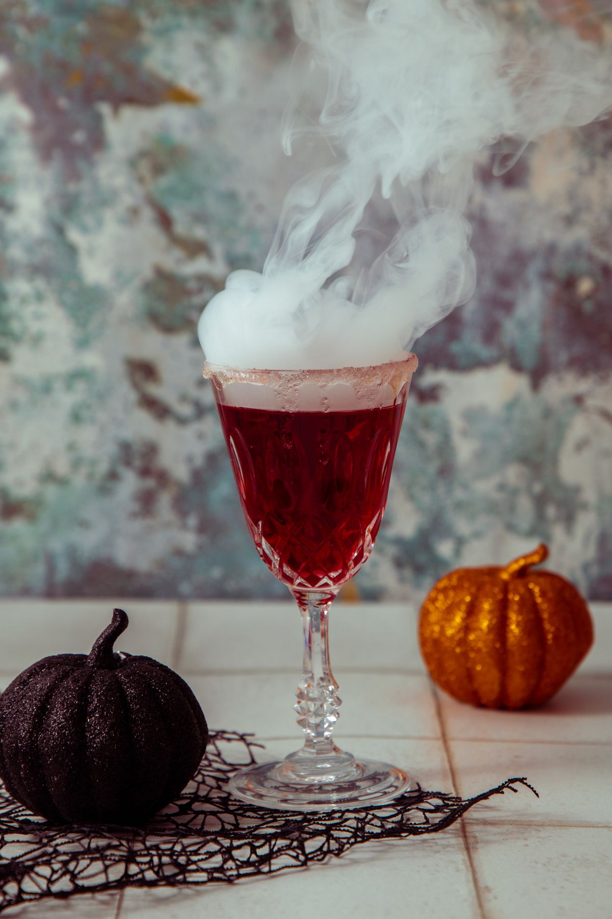 Deep red Halloween cocktail with a smoke effect and pumpkin decorations