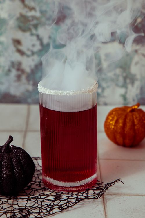 Free A steaming red cocktail in a glass, perfect for Halloween with decorative pumpkins. Stock Photo