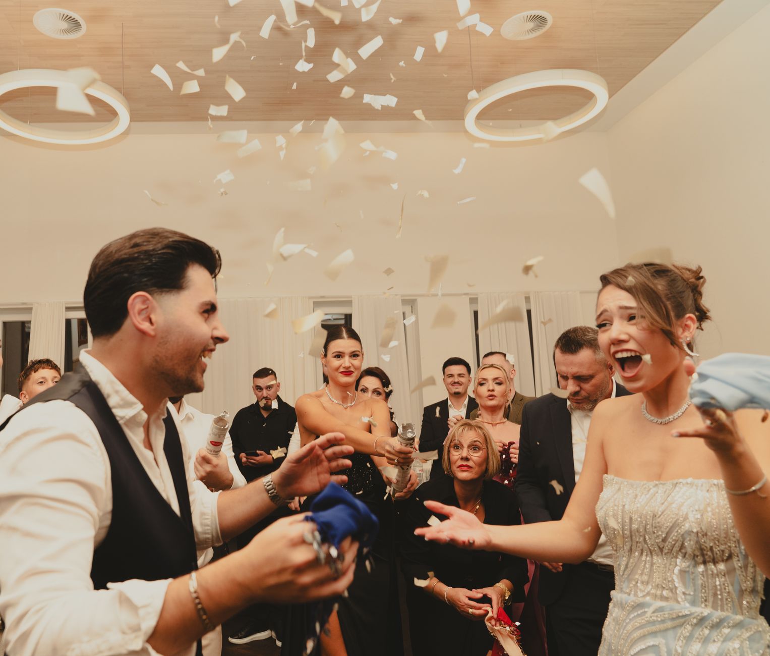 Bride and groom celebrating at a lively indoor wedding reception with friends and family.