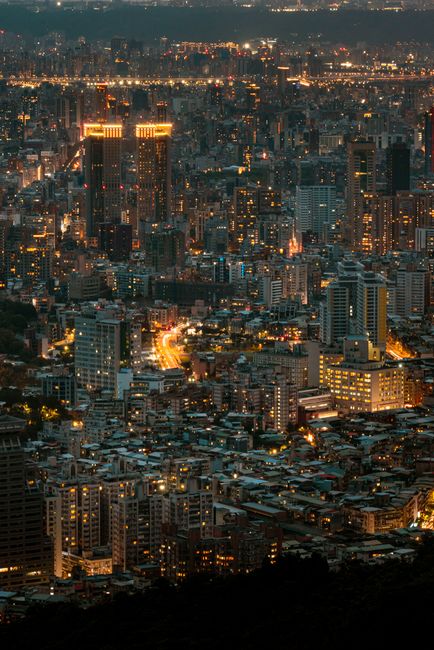 Stunning aerial view of Taipei's illuminated skyline at night, showcasing a bustling urban landscape.