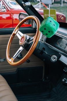 Vintage car interior showing a wooden steering wheel and hanging dice, evoking a classic vibe.
