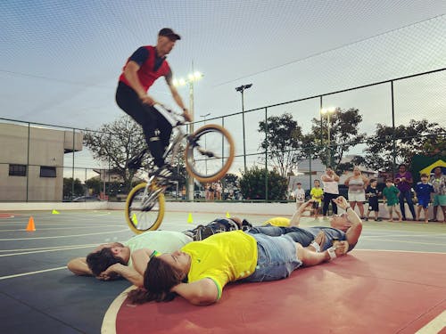 Man Jumping on Bike over People Lying Down